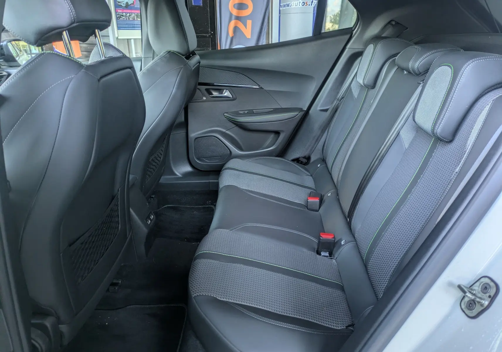 Vue intérieure côté droit des sièges arrière en cuir noir avec surpiqûres vertes du Peugeot 2008 GT 2022 blanc nacré.