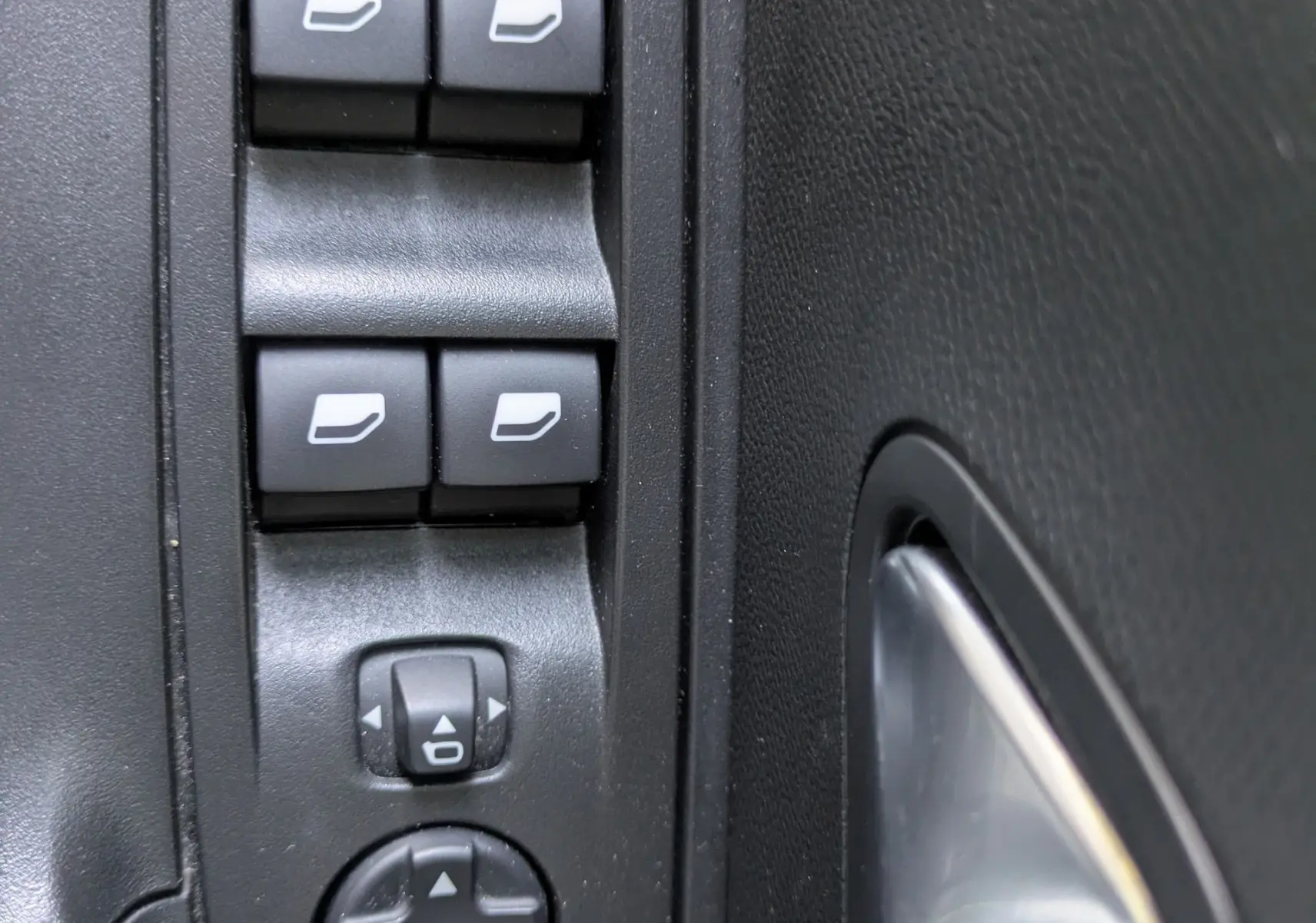 Gros plan sur les commandes de lève-vitres et réglage des rétroviseurs côté conducteur du Peugeot 2008 GT blanc nacré.