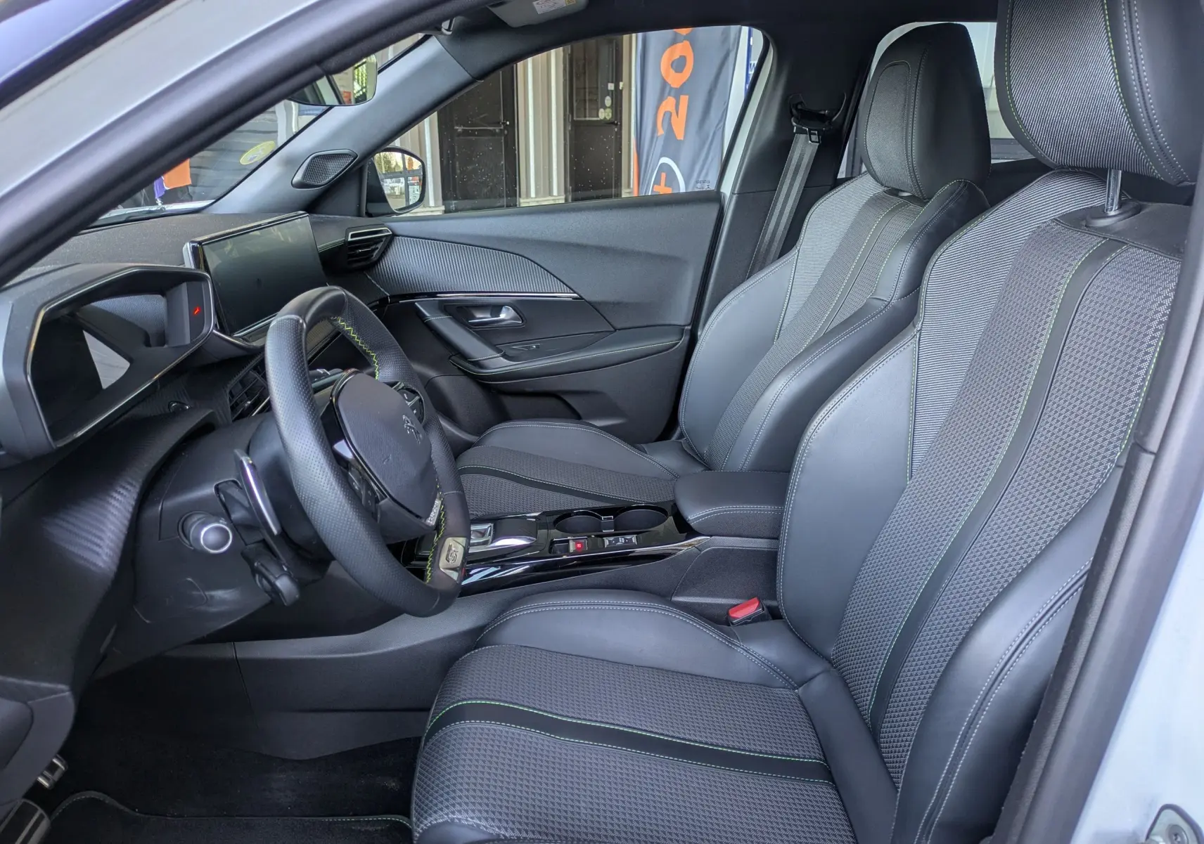 Vue intérieure côté conducteur du Peugeot 2008 GT 2022, sièges noirs avec surpiqûres vertes et tableau de bord moderne.