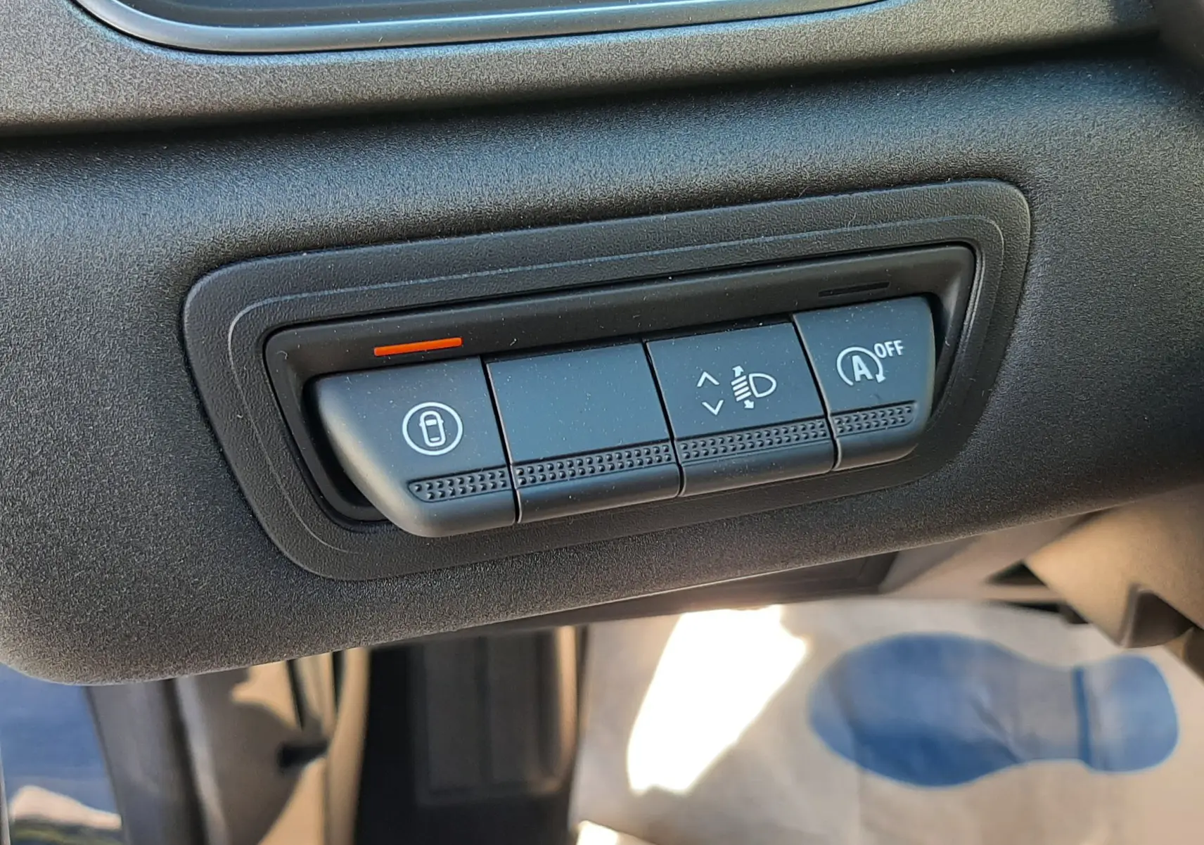 Gros plan sur les commandes de réglage des phares et verrouillage dans l'habitacle gris du Renault Captur Bleu Iron 2025.