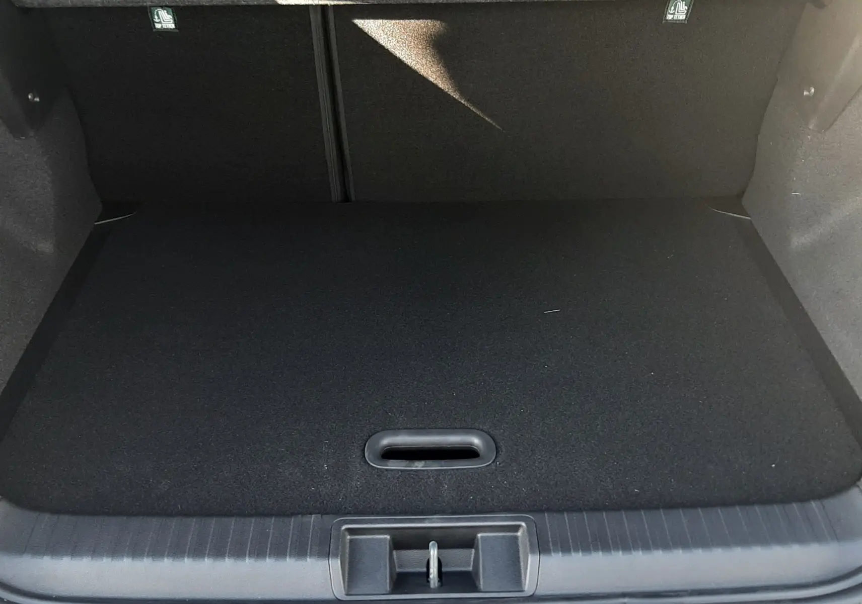 Coffre ouvert vu de l'arrière du Renault Captur II Ph.2 TCE 90CH TECHNO bleu Iron, espace de chargement vide et tapis noir.