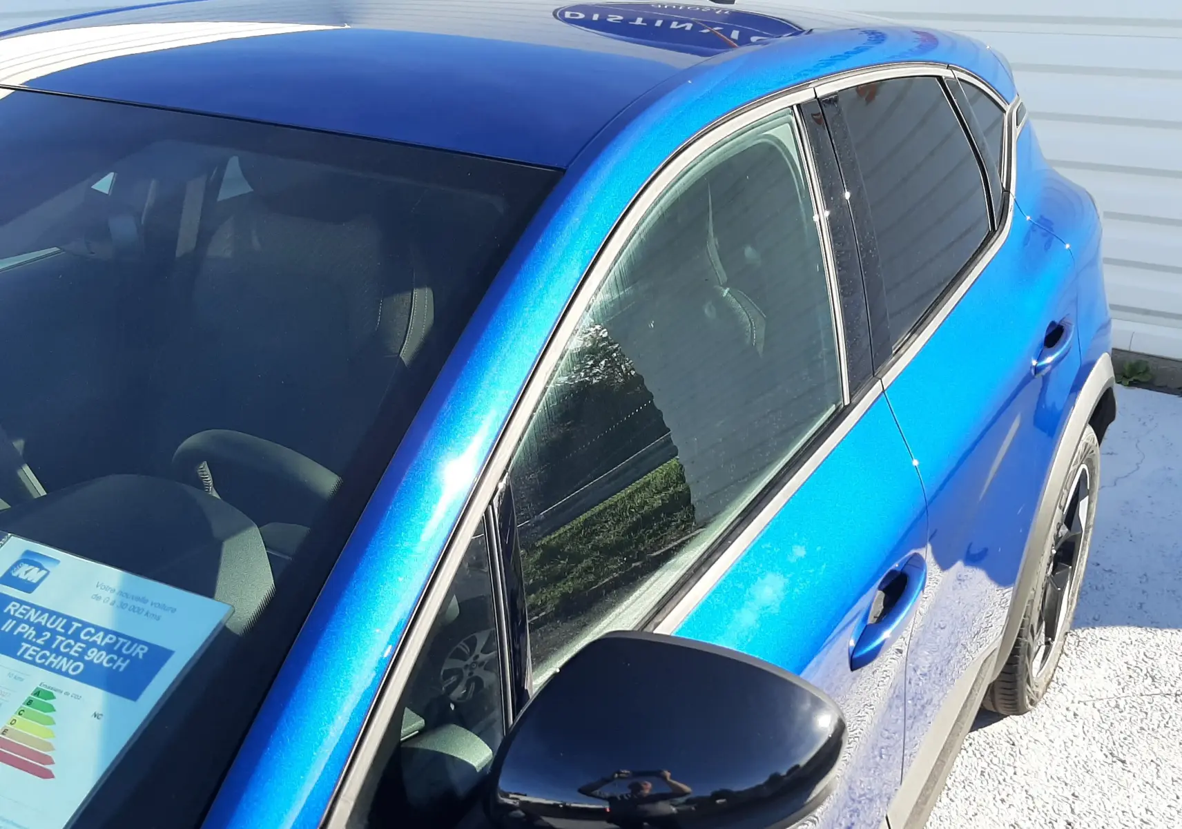 Vue de trois quarts avant droit du Renault Captur II Ph.2 TCE 90CH TECHNO bleu Iron avec rétroviseur noir brillant.