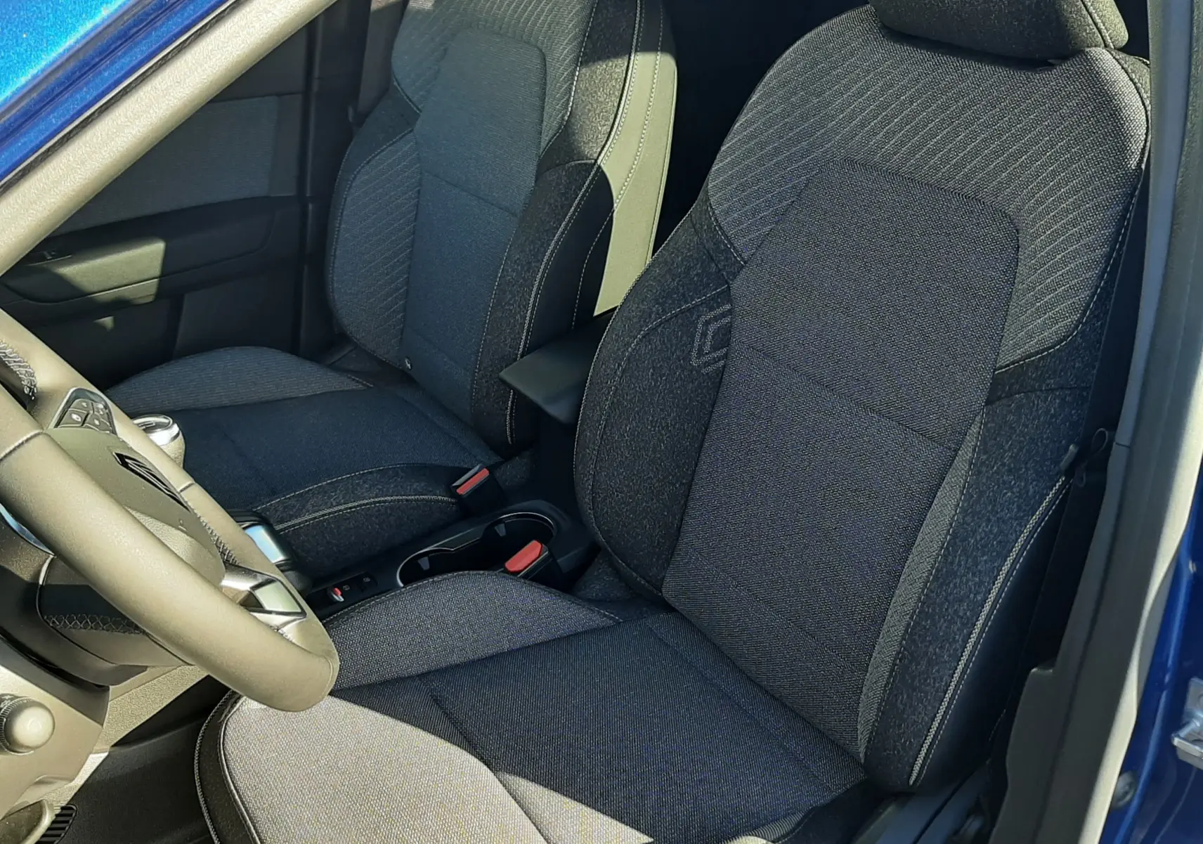 Vue intérieure côté conducteur du Renault Captur bleu Iron 2025, sièges tissu gris avec surpiqûres contrastées.