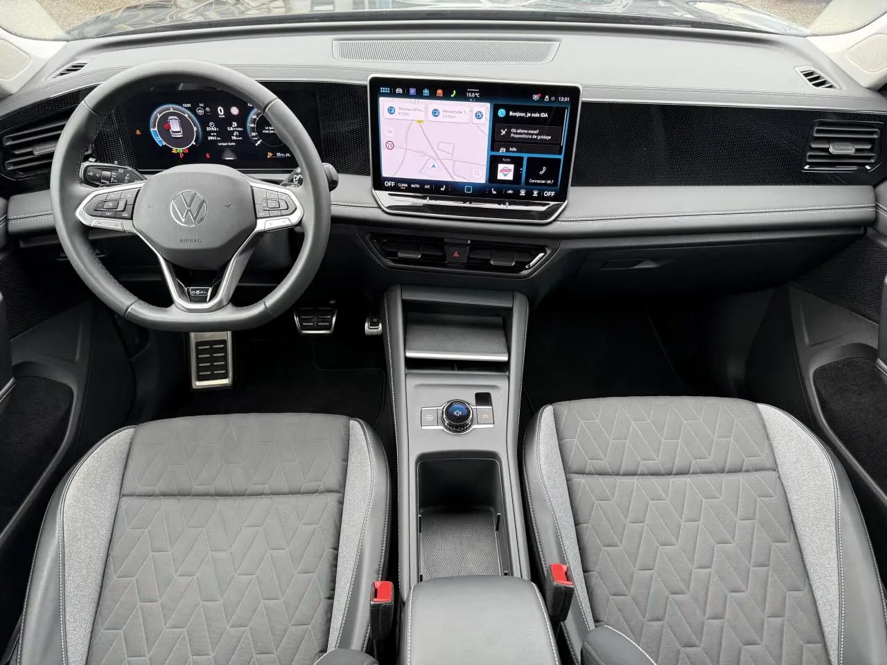 Vue intérieure frontale du Volkswagen Tiguan 2025, tableau de bord moderne avec écran tactile et sièges gris à motifs géométriques.