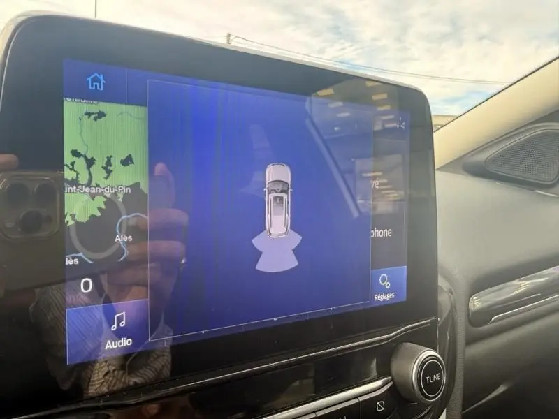 Écran tactile central du Ford Puma 2026 blanc montrant l'aide au stationnement et la navigation, vue intérieure côté droit.