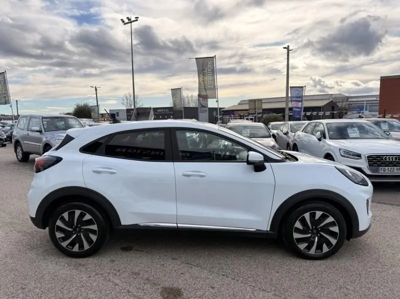 Vue de profil côté gauche d'un Ford Puma blanc 2026 stationné en extérieur, avec jantes noires et détails chromés.