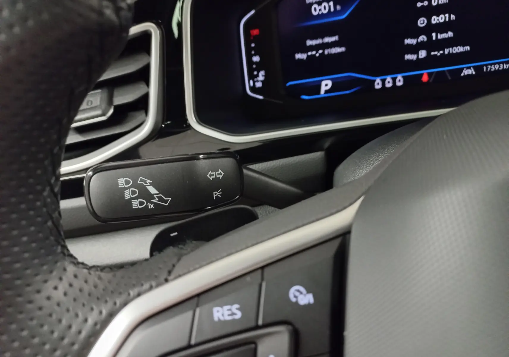 Gros plan sur le commodo de clignotants et le tableau de bord numérique du Volkswagen T-Roc 2025, intérieur noir.