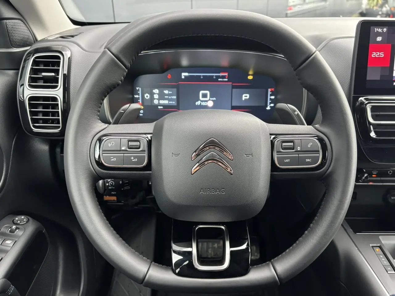 Vue centrée sur le volant cuir noir du Citroën C5 Aircross 2025 avec tableau de bord numérique et écran tactile latéral.