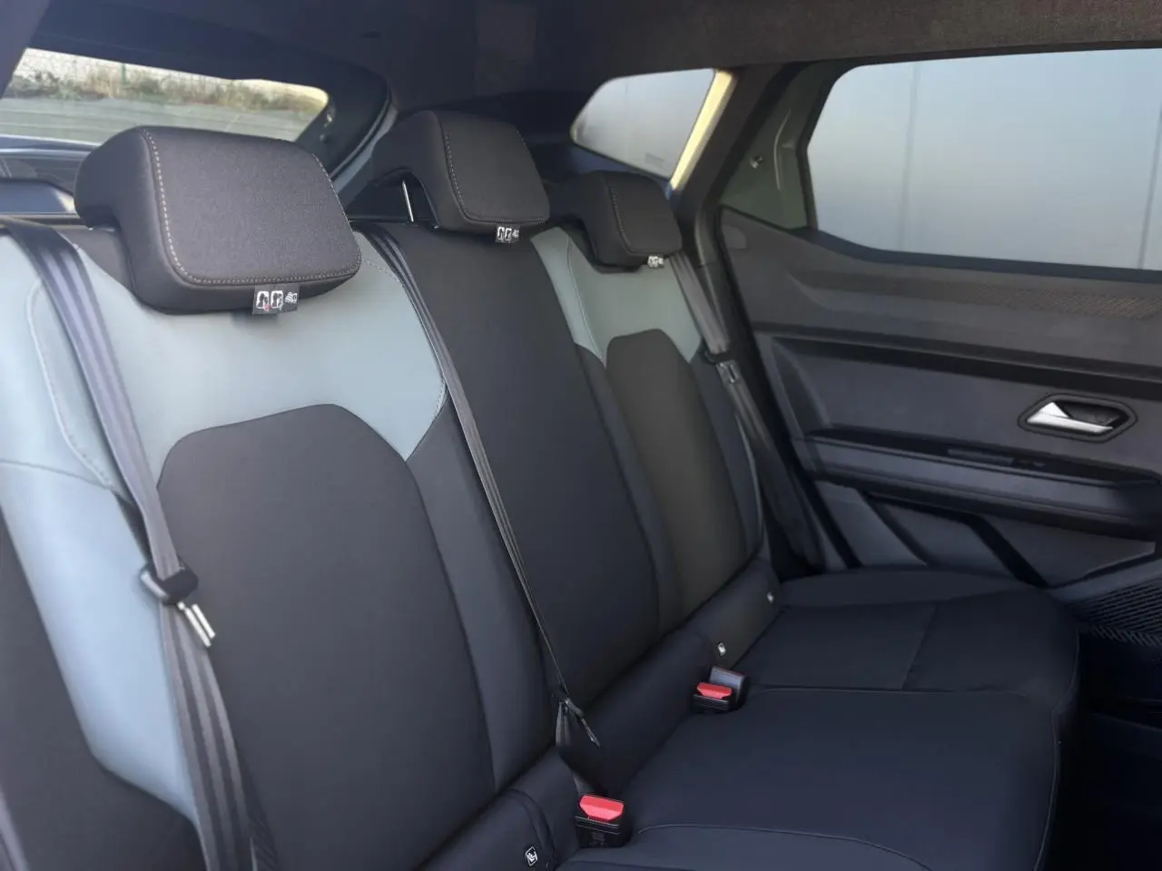 Vue latérale droite de la banquette arrière noire et grise du Dacia Duster 2026 avec ceintures et appuie-têtes intégrés.