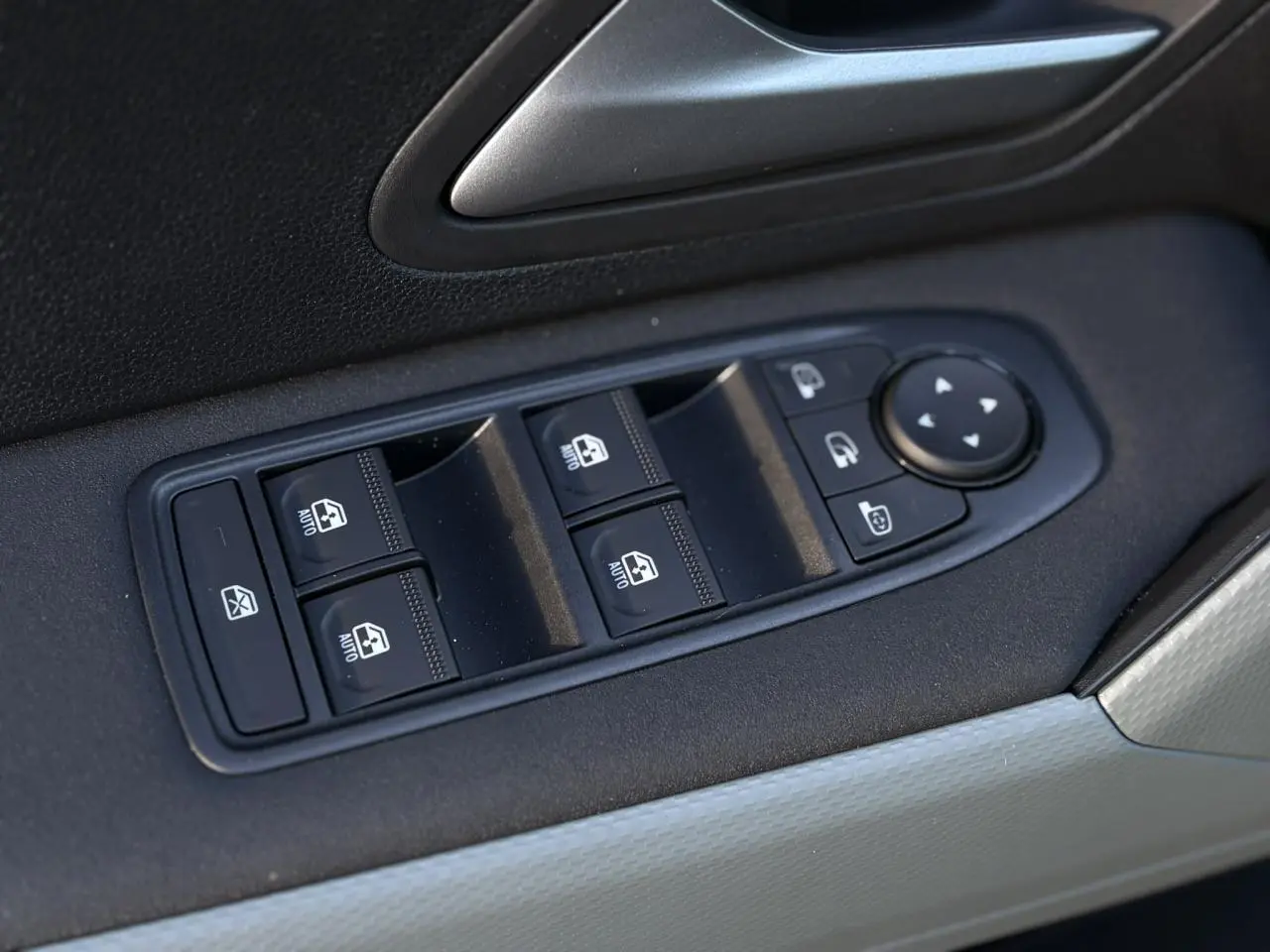 Gros plan sur les commandes des vitres électriques et rétroviseurs sur la porte côté conducteur du Dacia Duster 2026.