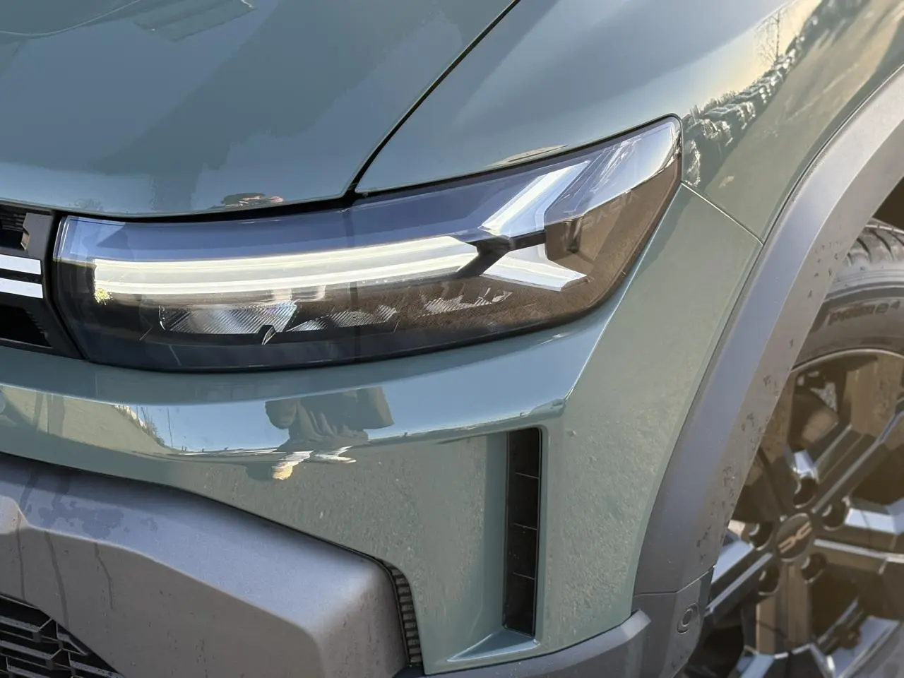 Gros plan sur le phare avant droit du Dacia Duster 2026 kaki lichen avec jante alliage noire et détails du pare-chocs.