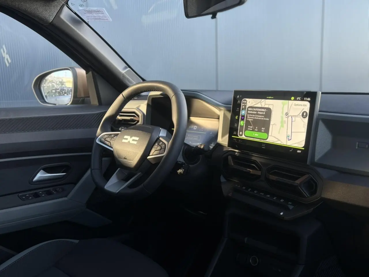 Vue intérieure côté conducteur du Dacia Duster 2026 avec volant multifonction et écran tactile central affichant la navigation.