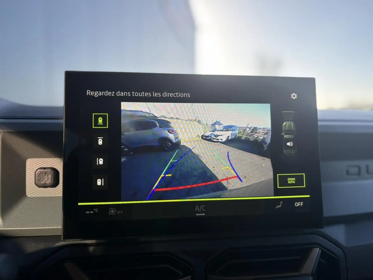 Écran tactile intérieur montrant la caméra multivues du Dacia Duster kaki en vue arrière avec guidage de stationnement.
