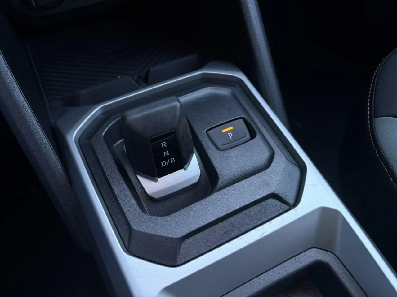 Gros plan sur la commande de boîte automatique noire et grise du Dacia Duster Eco-G 120, avec bouton de parking éclairé.