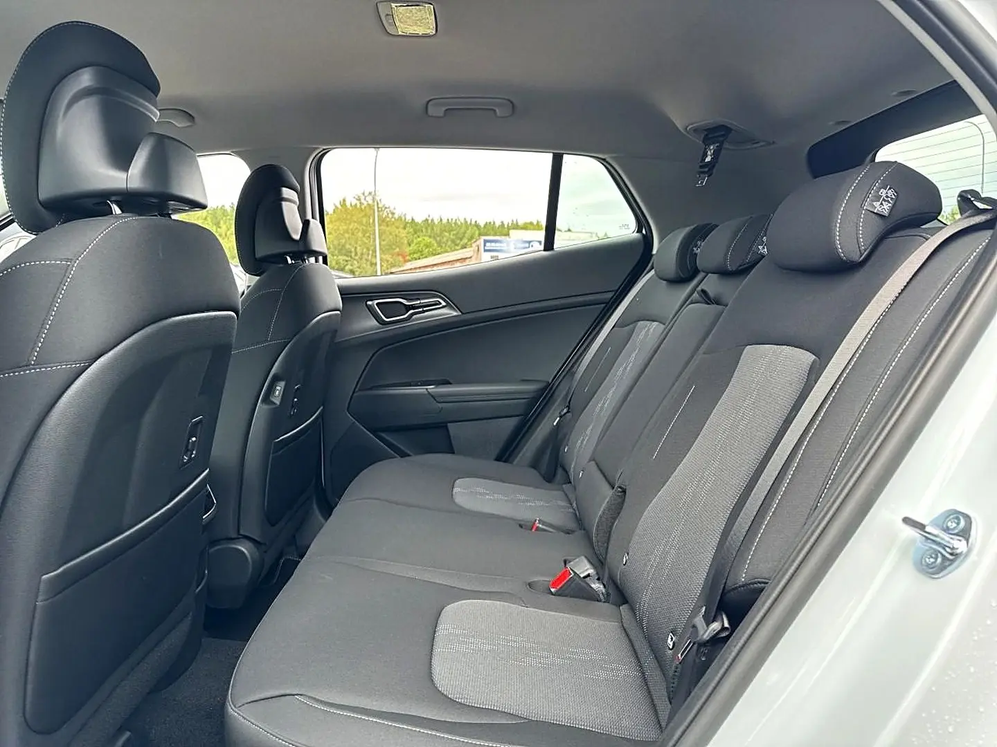 Vue intérieure côté droit sur la banquette arrière noire et grise du Kia Sportage blanc 2026, avec appuie-têtes réglables.
