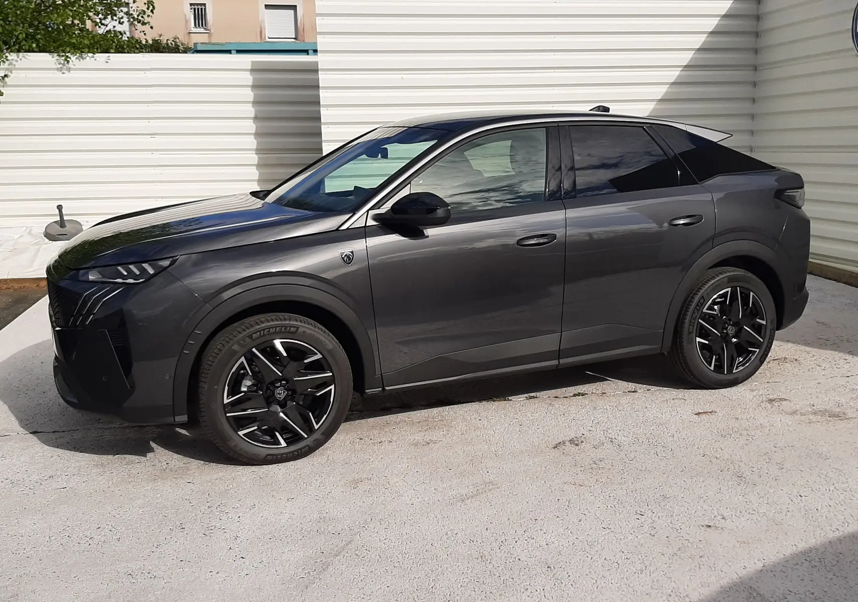 Peugeot 3008 hybride gris titane avec toit noir, vue de profil côté gauche, jantes noires distinctives.