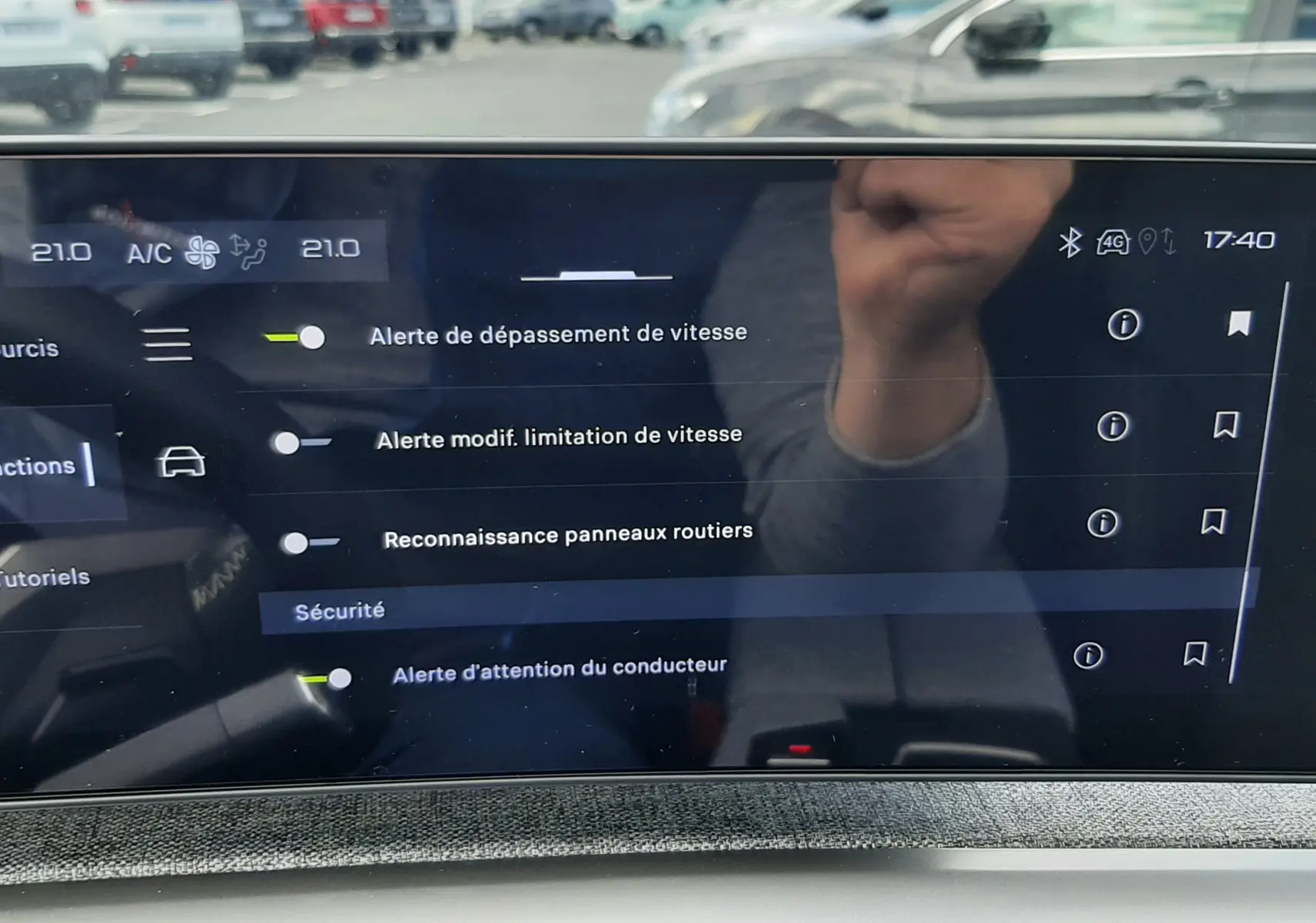 Écran tactile intérieur du Peugeot 3008 2026 montrant les réglages d’alerte sécurité, avec reflet et vue floue extérieure.