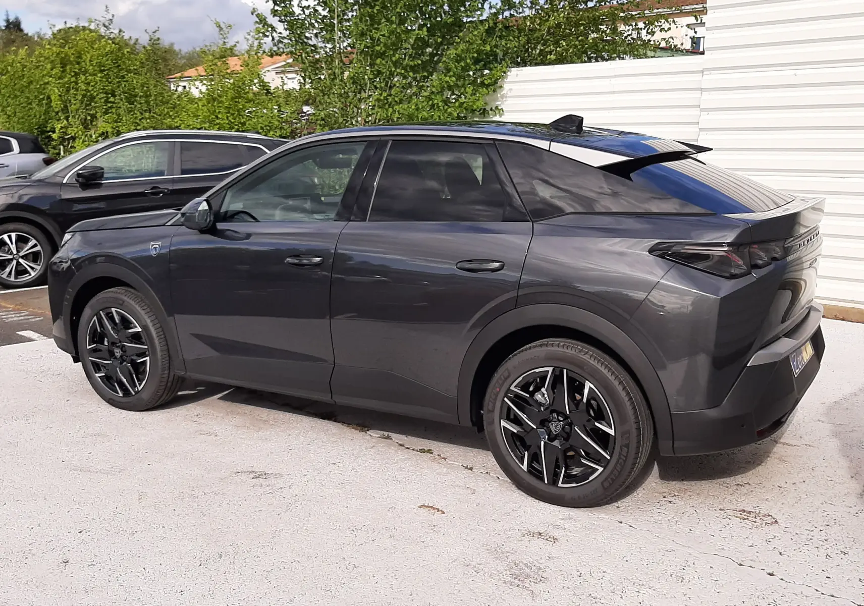 Peugeot 3008 gris titane avec toit noir, vue de profil côté gauche, jantes noires et lignes modernes marquées.