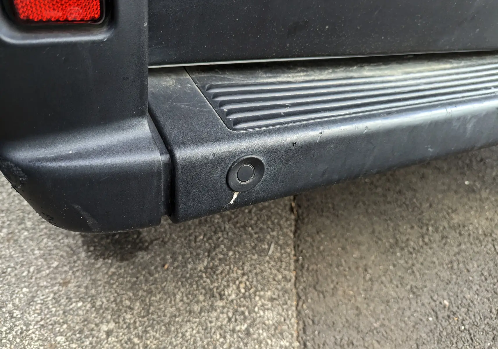 Gros plan sur le pare-chocs arrière noir du Fiat Ducato Fourgon blanc, montrant un capteur de recul circulaire.