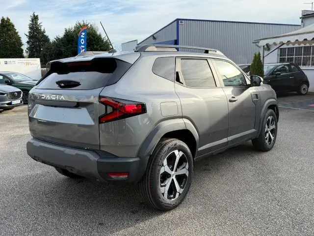 Vue 3/4 arrière droite du Dacia Duster 1.8 Hybrid 155 Journey gris schiste avec jantes bi-ton et sellerie spécifique.