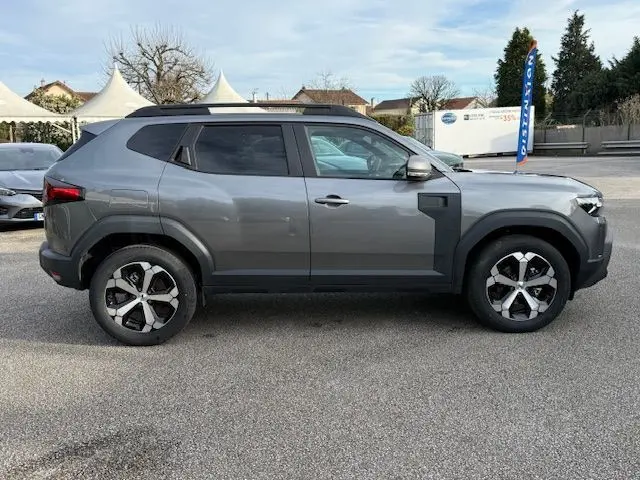 Vue de profil côté droit du Dacia Duster 1.8 Hybrid 155 Journey gris schiste avec jantes bi-ton et toit noir.