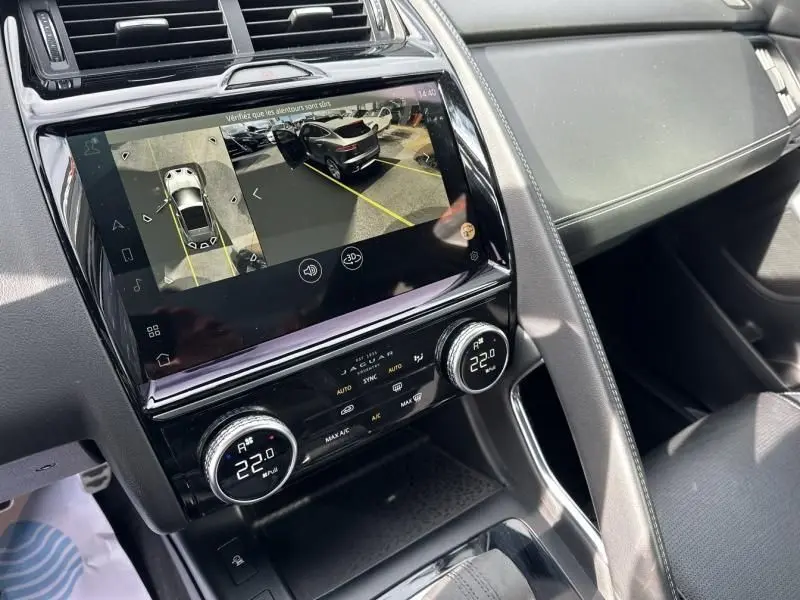 Vue intérieure du tableau de bord du Jaguar E-PACE noir 2021, écran affichant la caméra de recul et commandes climatisation.