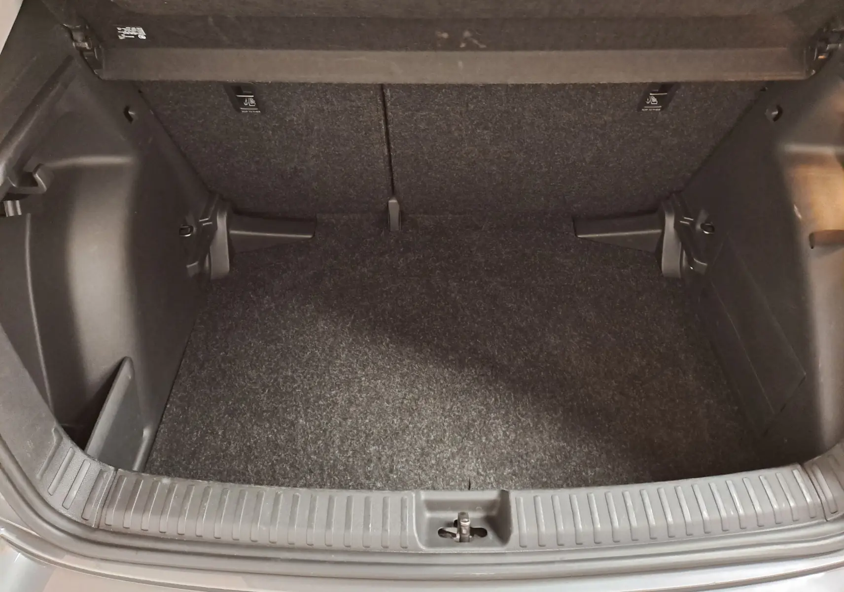 Coffre ouvert vu de dessus d'une Skoda Fabia 2025 gris graphite, montrant l'espace de rangement vide et le seuil de chargement.
