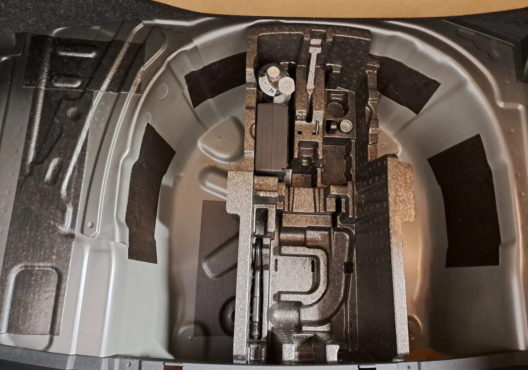 Vue plongeante sur le rangement sous coffre d'une Skoda Fabia 2025, montrant l'emplacement pour roue de secours et outils.