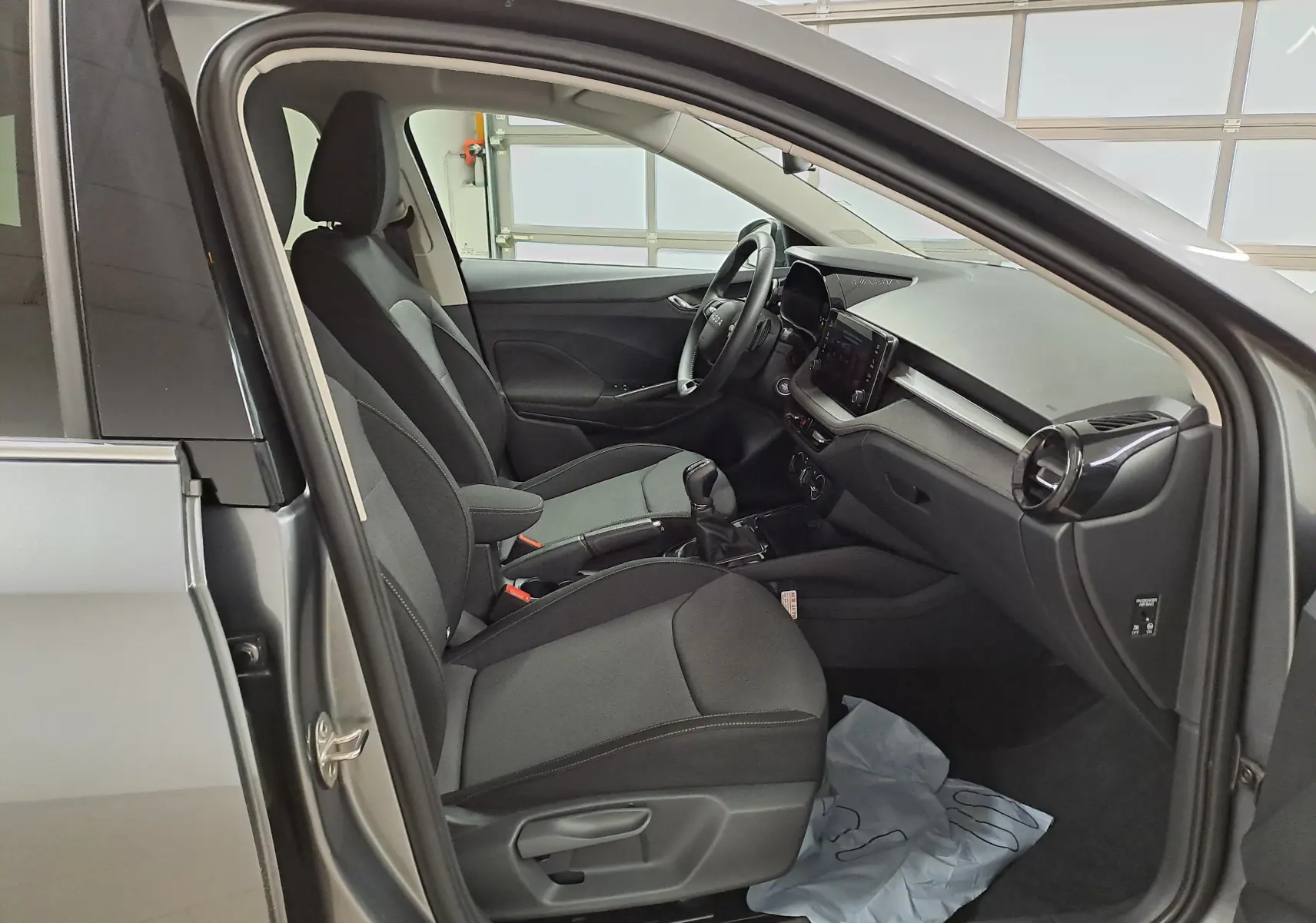 Vue intérieure côté conducteur de la Skoda Fabia 2025 gris graphite, sièges tissu noirs et tableau de bord moderne.