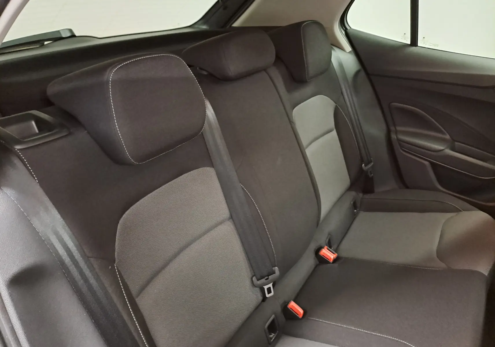 Vue intérieure de la banquette arrière de la Skoda Fabia 2025, sièges tissu gris et noir avec ceintures visibles.