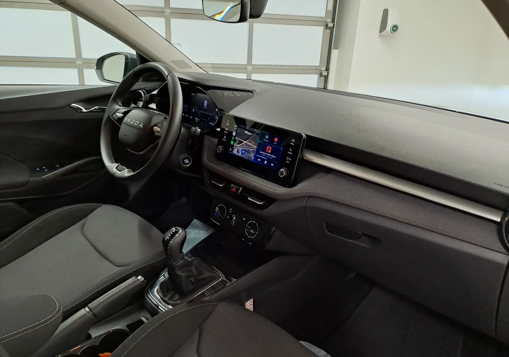 Vue intérieure côté conducteur du Skoda Fabia 2025, tableau de bord noir avec écran tactile central et volant multifonction.