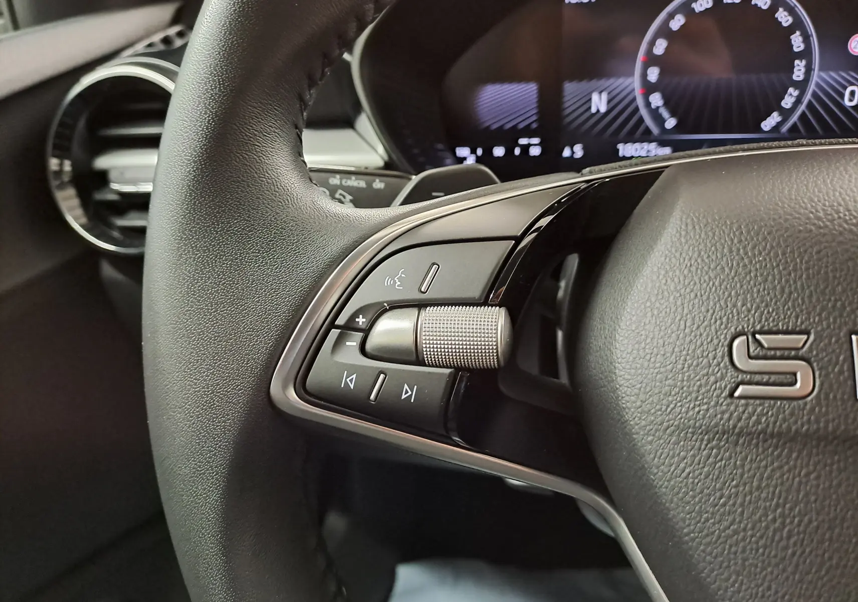 Gros plan sur les commandes gauche du volant cuir noir d'une Skoda Fabia 2025 avec tableau de bord numérique en arrière-plan.