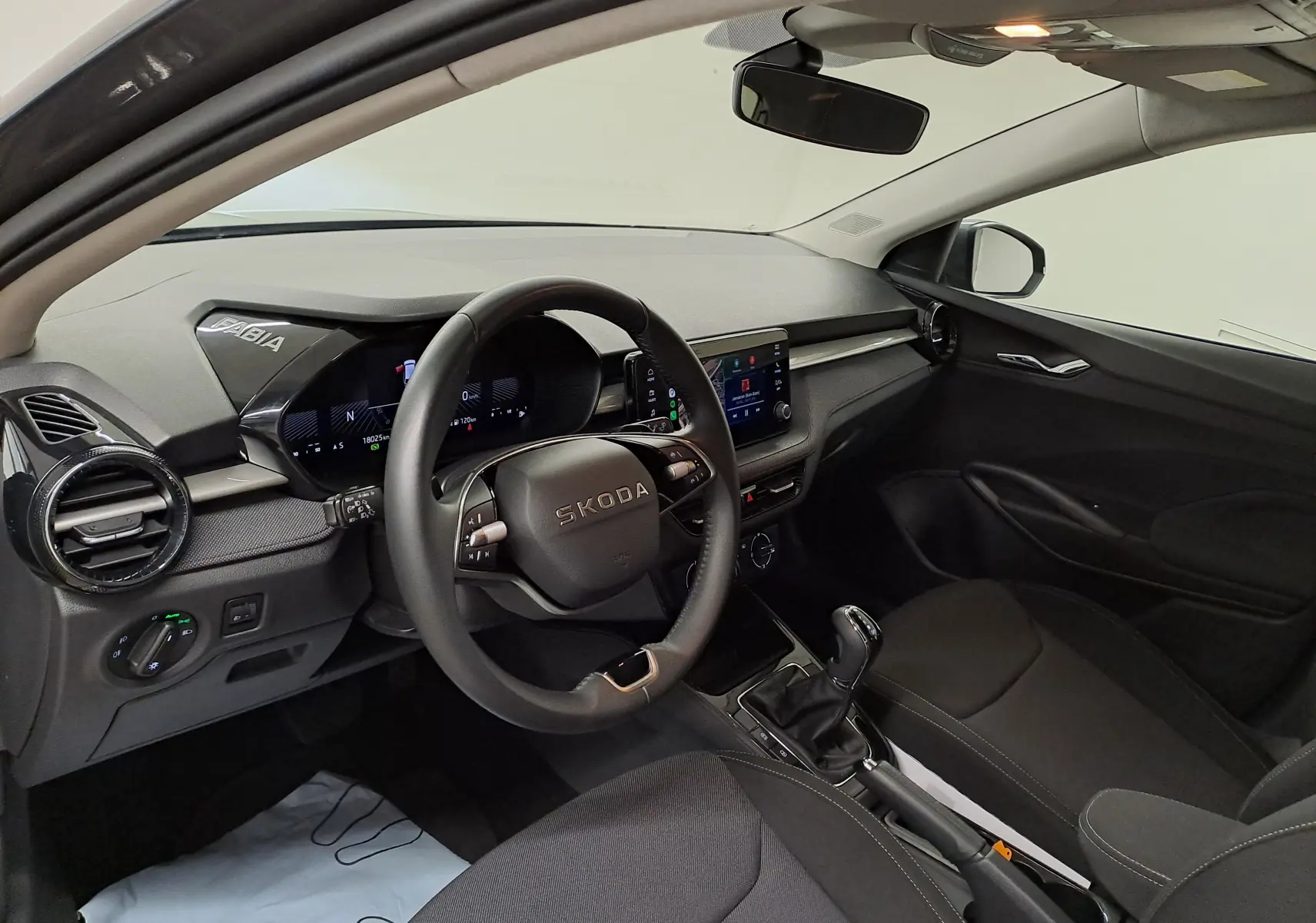 Vue intérieure avant droite du Skoda Fabia 2025 avec tableau de bord noir et volant multifonction.