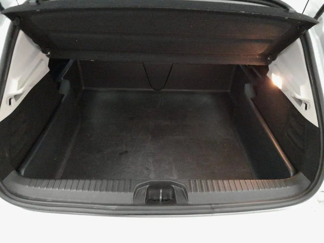 Coffre ouvert vu de face d'une Renault Clio gris clair, montrant l'espace de chargement vide et l'éclairage intérieur.