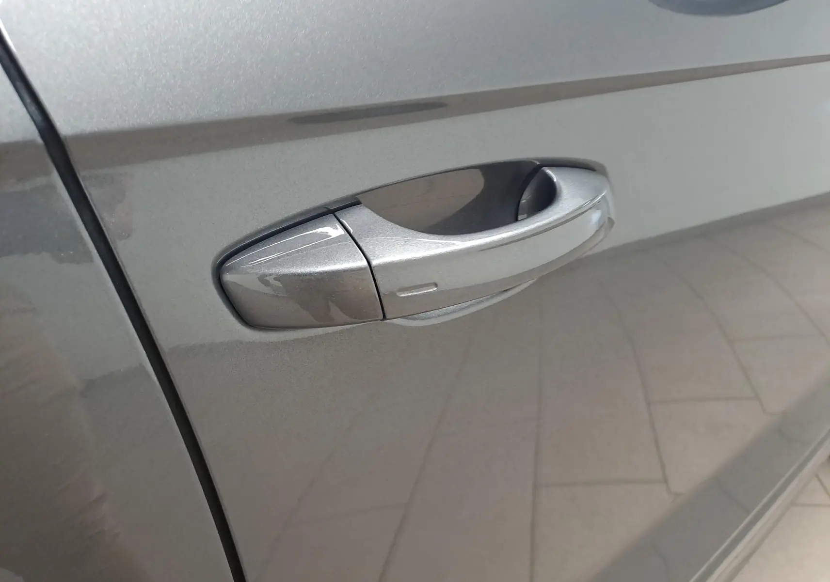 Poignée de porte côté gauche en gros plan sur Volkswagen T-Roc 2025 gris Indium métallisé.
