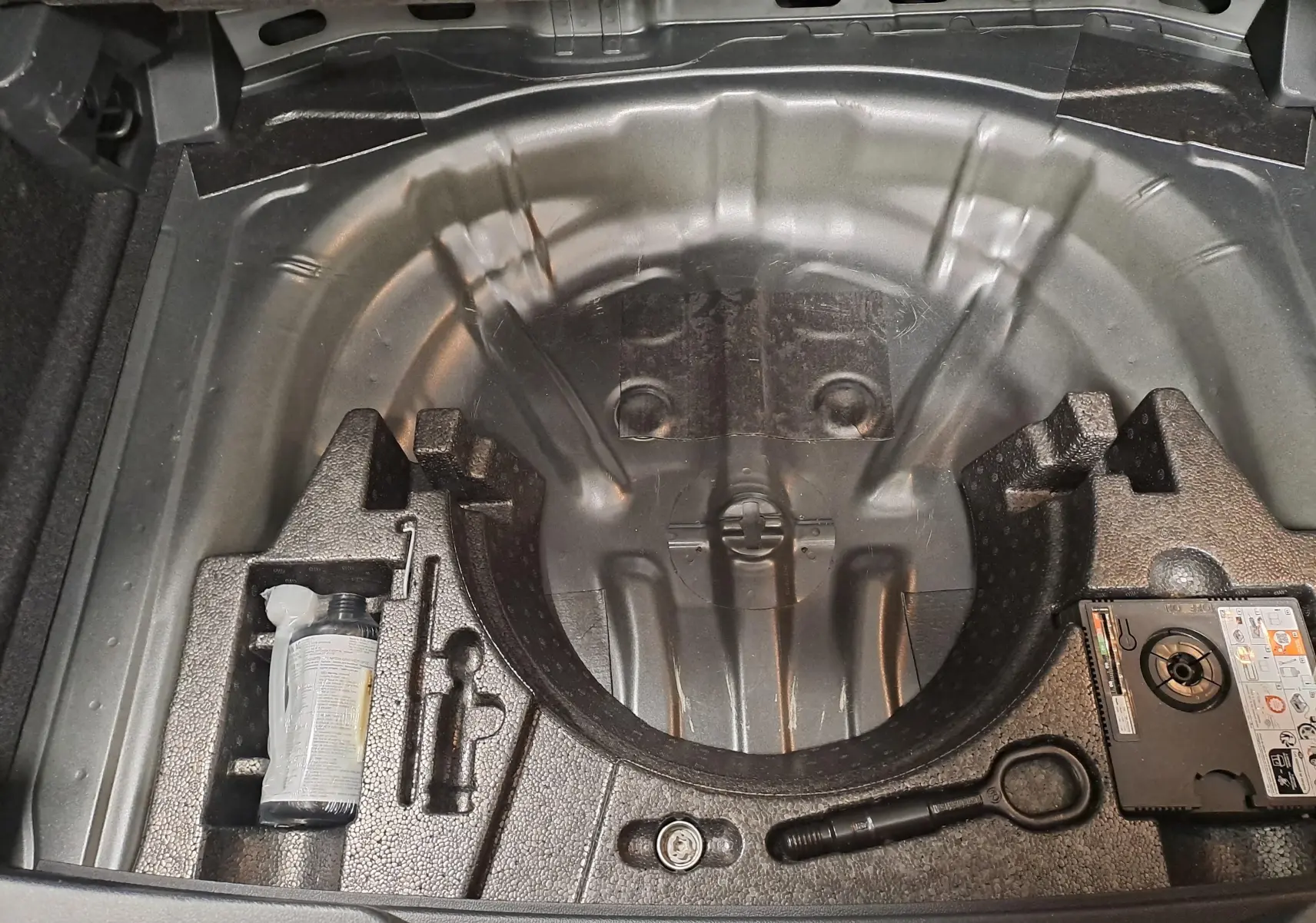 Coffre ouvert en vue plongeante du Volkswagen T-Roc 2025, montrant le rangement sous plancher sans roue de secours.