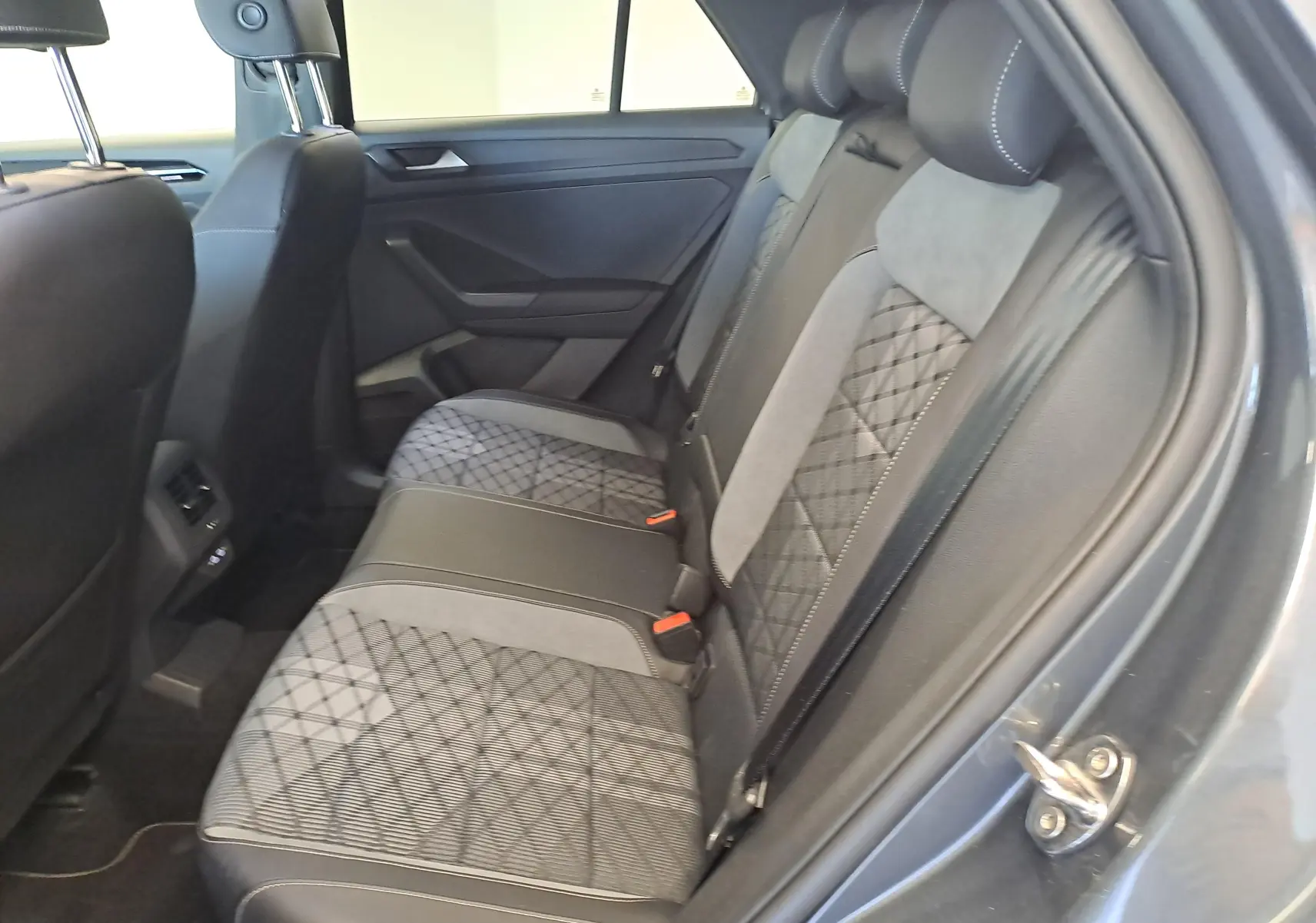 Vue intérieure côté droit des sièges arrière du Volkswagen T-Roc 1.5 TSI 2025 avec sellerie tissu et cuir gris à motifs géométriques.