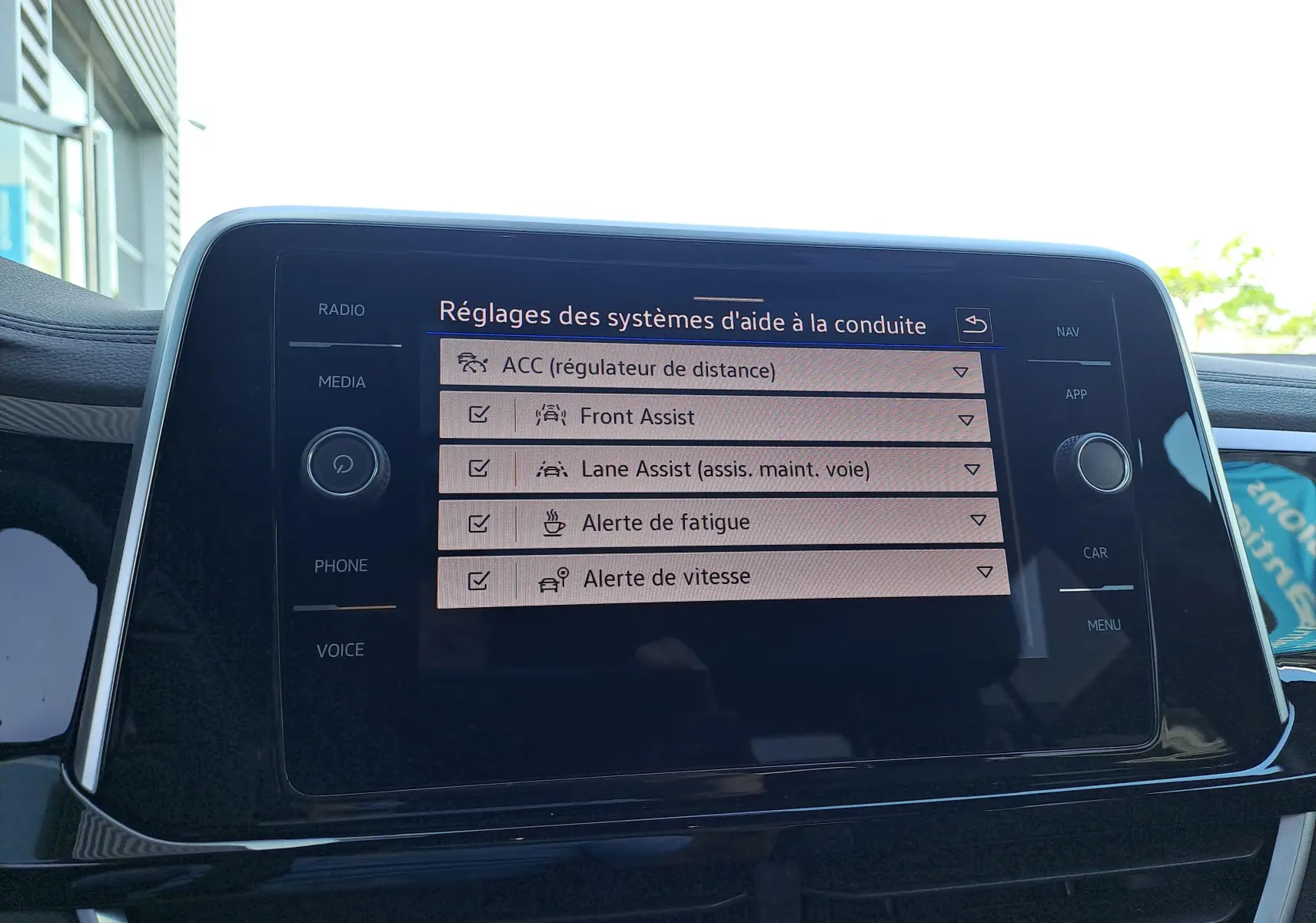 Écran tactile central du Volkswagen T-Roc 2025 affichant les réglages des aides à la conduite en intérieur.