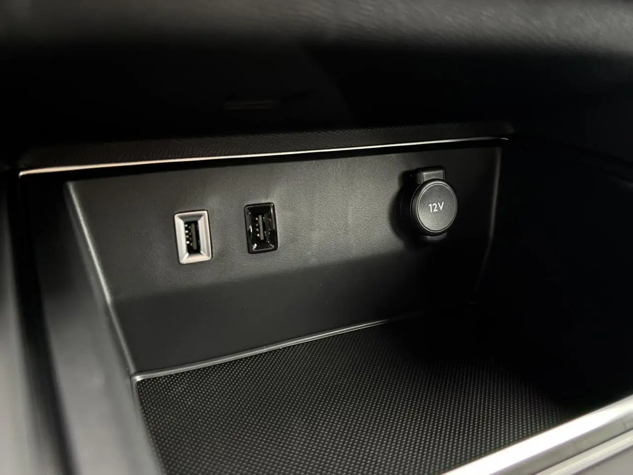 Vue rapprochée de la prise 12V et des ports USB dans le compartiment avant du Citroën C5 Aircross blanc Okénite 2025.