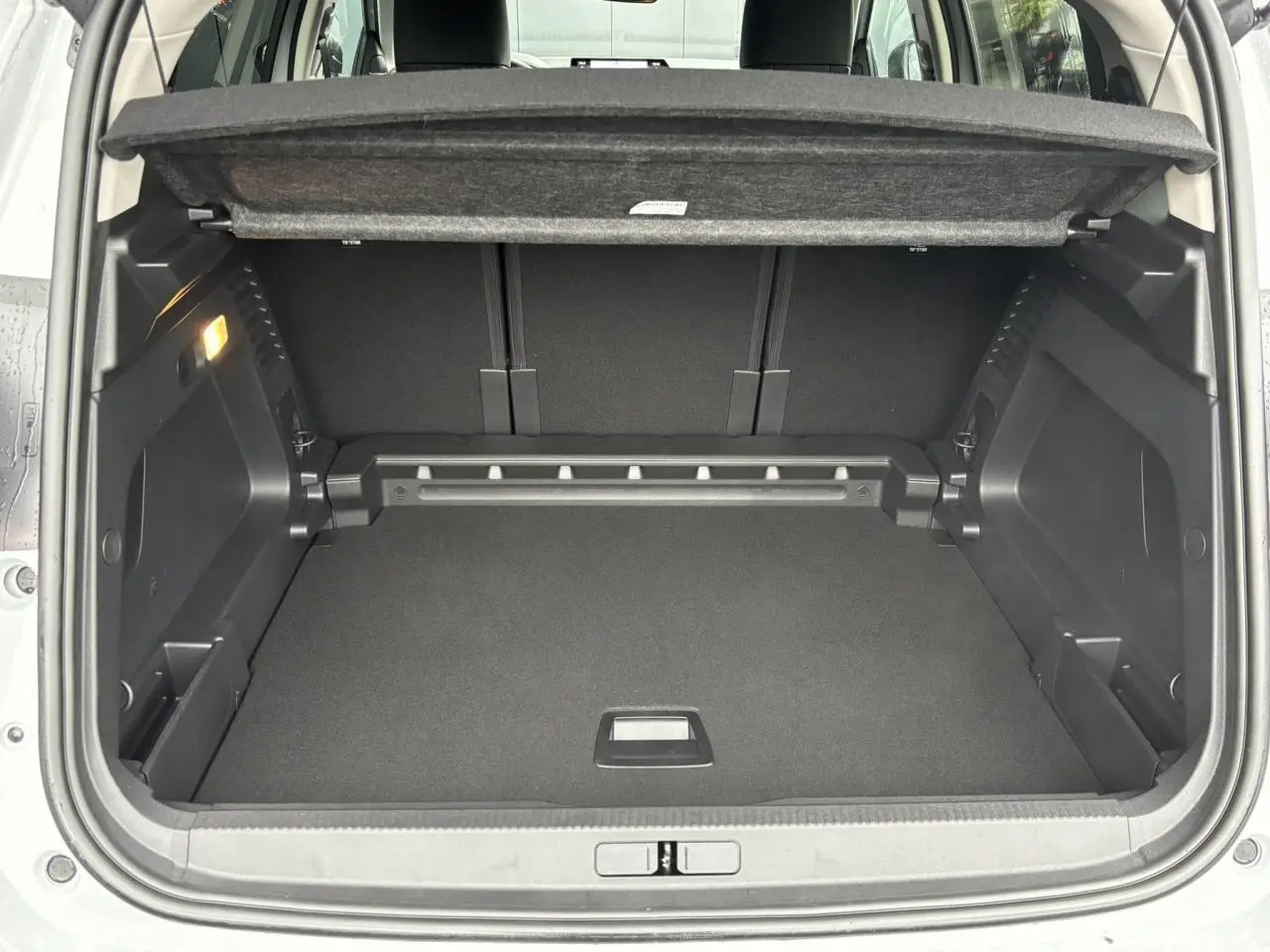 Coffre ouvert vu de l'arrière d'un Citroën C5 Aircross blanc Okénite, montrant un espace de chargement propre et modulable.