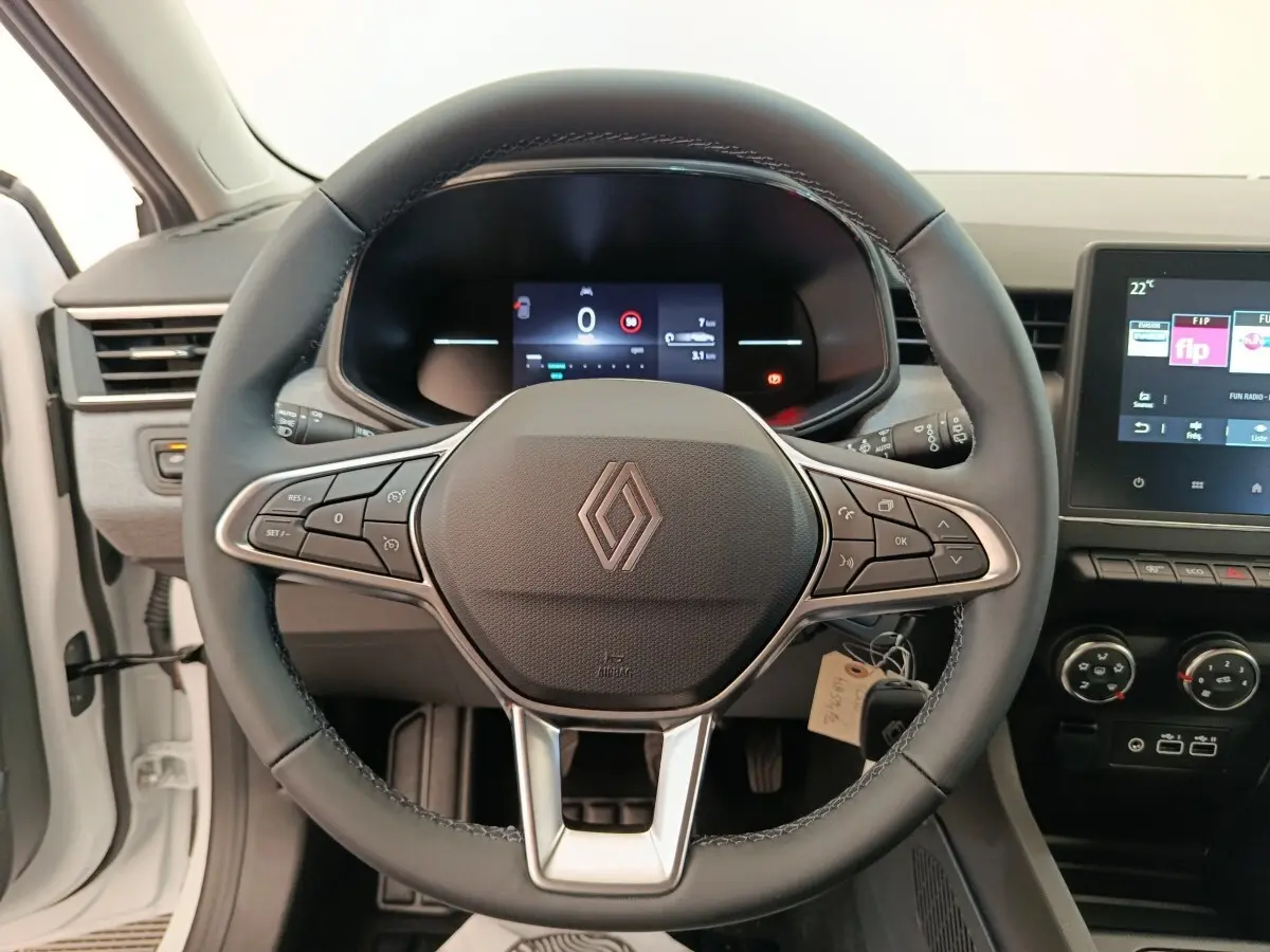 Vue intérieure centrée sur le volant cuir noir de la Renault Clio blanc 2024 avec tableau de bord digital et écran tactile.