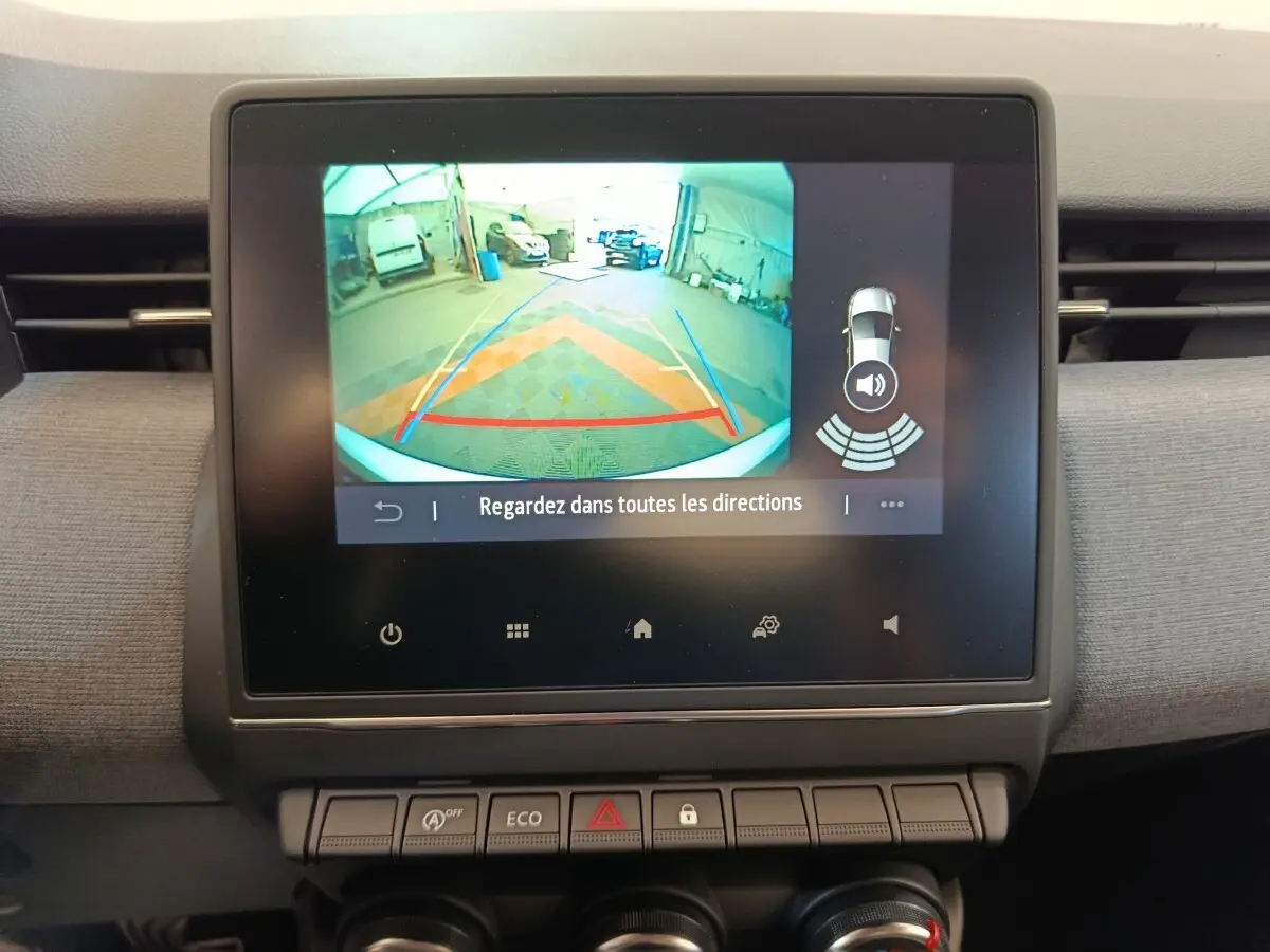 Écran tactile central montrant la caméra de recul et l’aide au stationnement dans un Renault Clio blanc, vue intérieure.