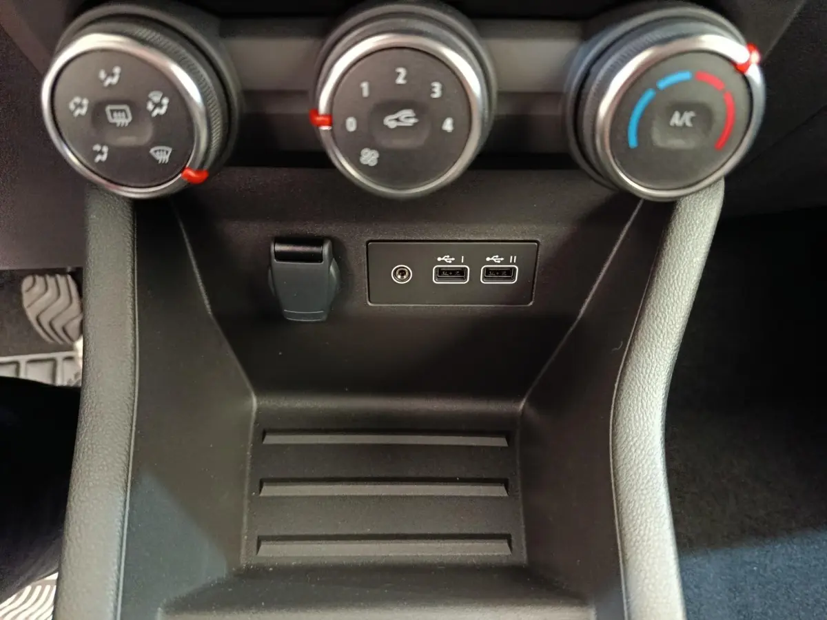 Vue rapprochée de la console centrale noire de la Renault Clio 2024 montrant les commandes de climatisation et ports USB.