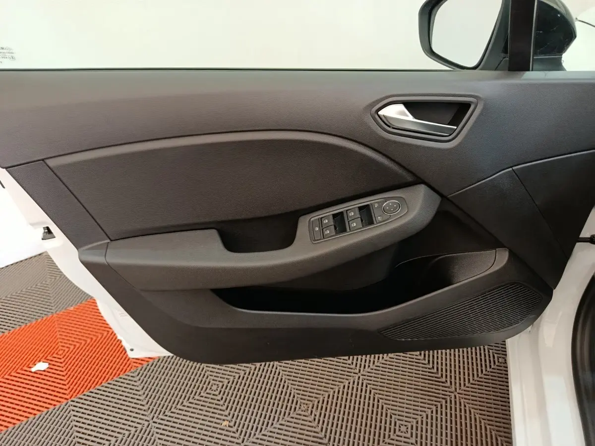 Vue intérieure de la porte avant gauche noire de la Renault Clio blanche 2024 avec commandes électriques des vitres.