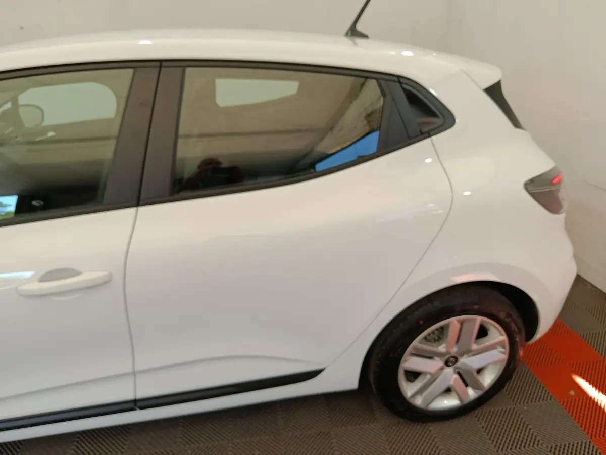 Vue latérale côté droit d'une Renault Clio blanche 2024, mettant en valeur la porte arrière et la roue arrière.