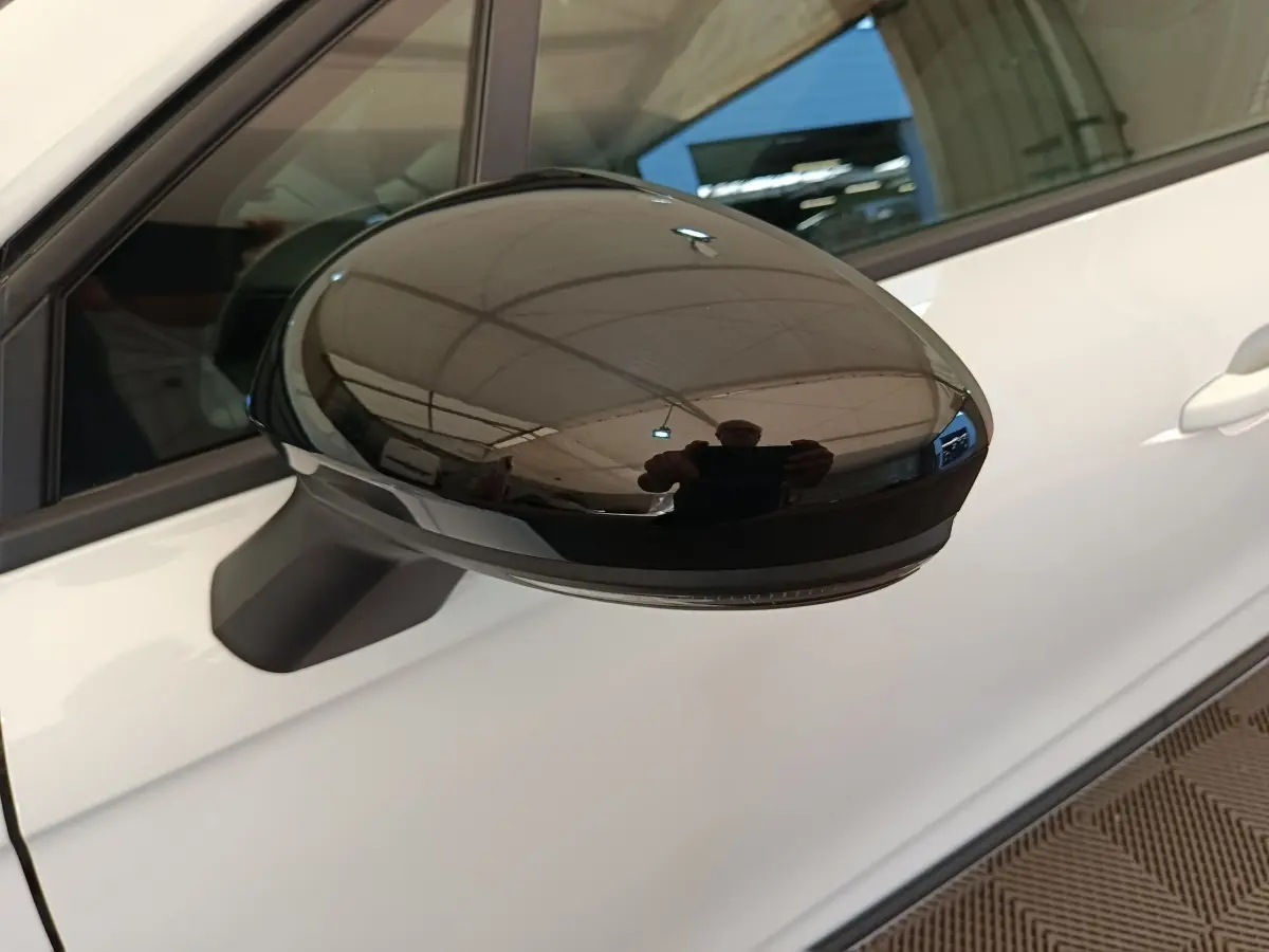 Rétroviseur noir côté gauche d’une Renault Clio blanche 2024, vue rapprochée sur la portière avant.