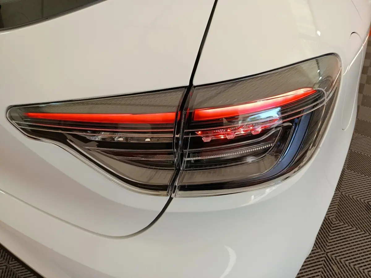 Gros plan sur le feu arrière droit rouge et noir d'une Renault Clio blanche 2024, vue arrière côté droit.
