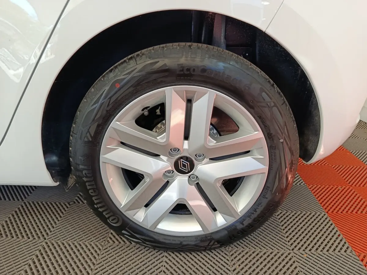 Gros plan sur la roue avant droite d'une Renault Clio blanche, mettant en valeur la jante alliage argentée et le pneu Continental.
