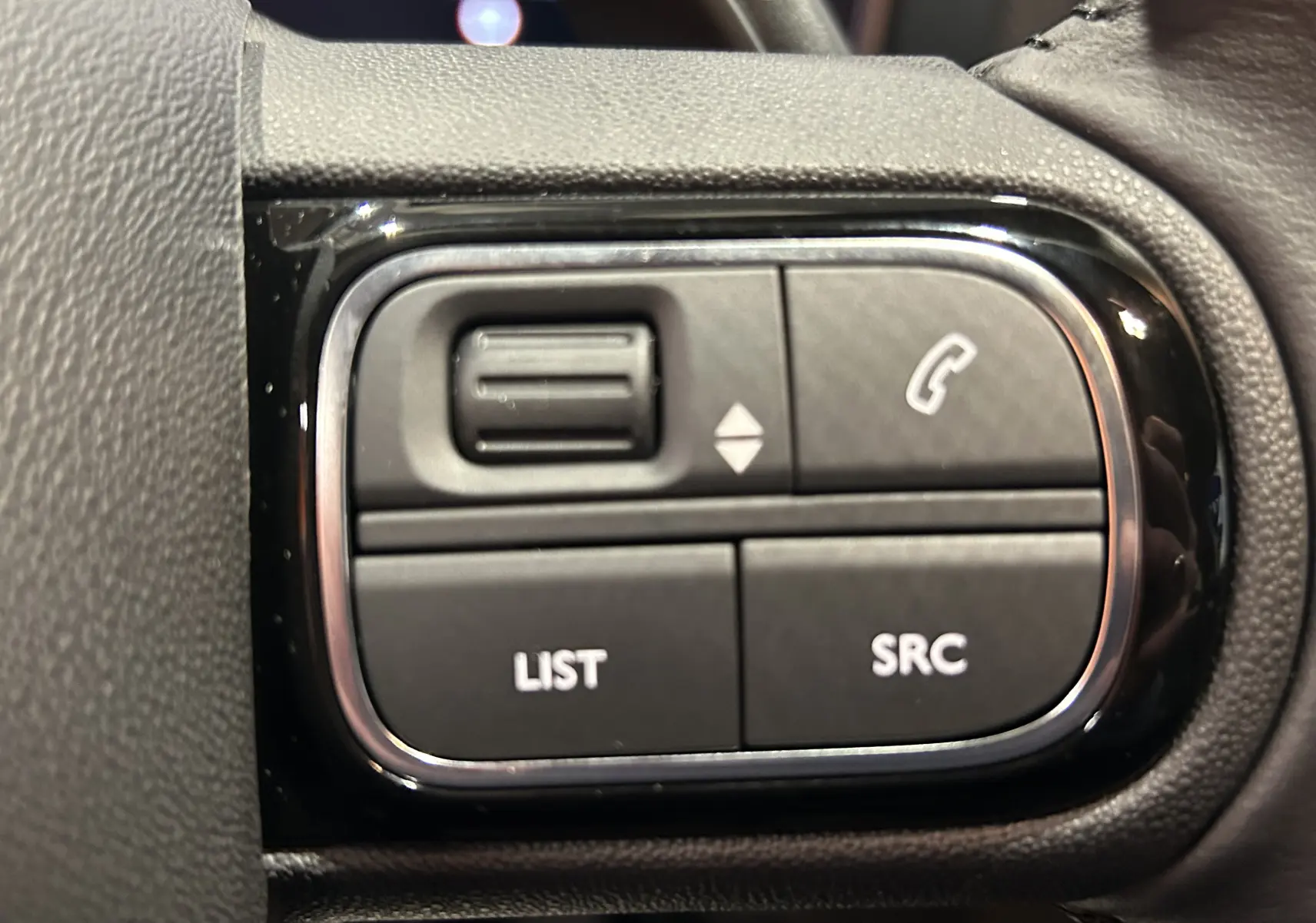 Gros plan sur les commandes au volant du Citroën C5 Aircross 2025, finition cuir noir et détails chromés.