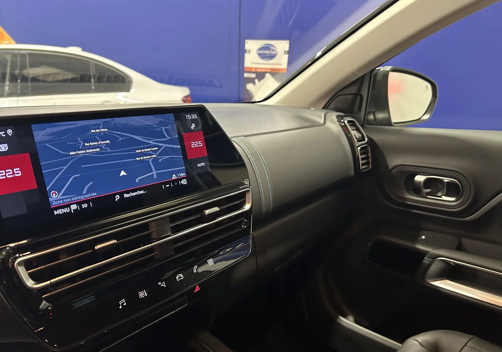 Intérieur du Citroën C5 Aircross 2025 côté passager, tableau de bord noir avec écran GPS et coutures bleues.